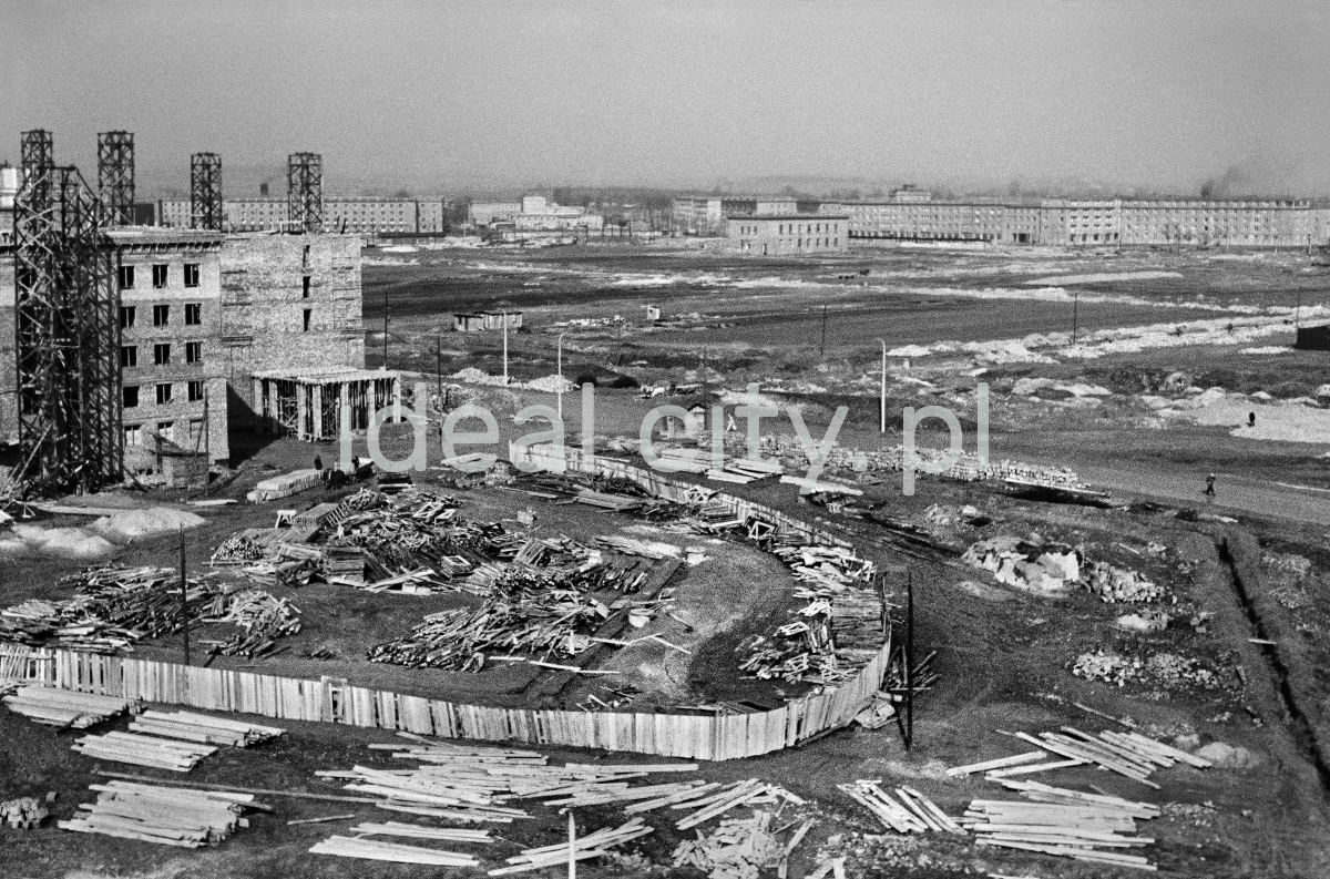 A view of the construction site from above, in the foreground a wooden fence fenced in. Chaos on both sides.
