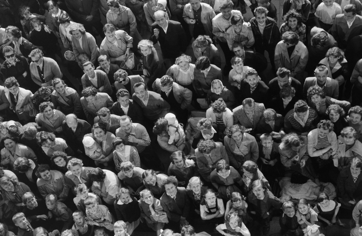 View from the height of the first floor of the people gathered in front of the building, looking at the lens.