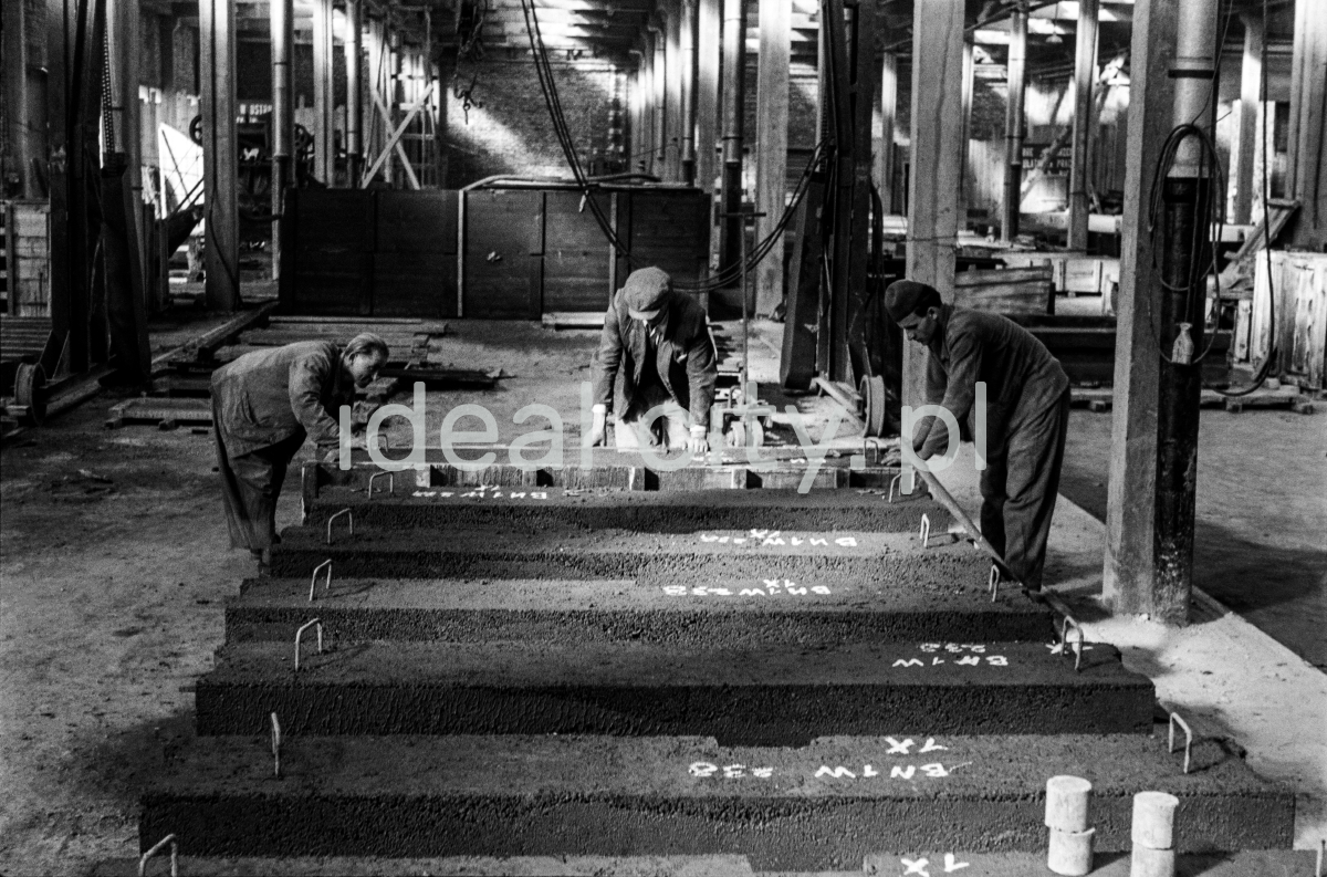 Workers place newly poured prefabricated concrete blocks in the production hall.