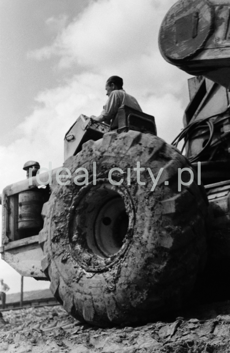 A man on a tractor, shot from below - a massive tire in the foreground.