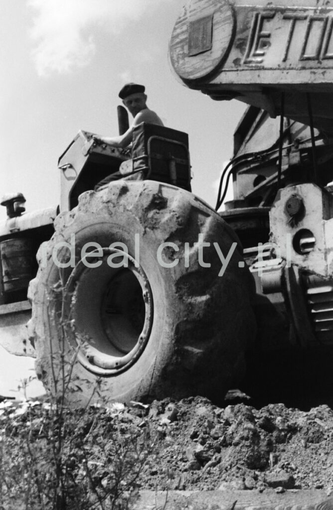 A man on a tractor, shot from below - a massive tire in the foreground.