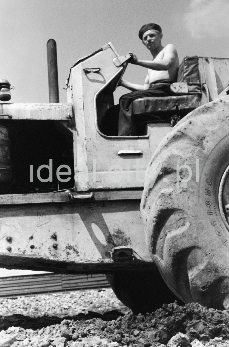 A man on a tractor, shot from below - a massive tire in the foreground.