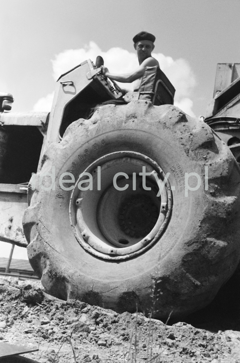 A man on a tractor, shot from below - a massive tire in the foreground.