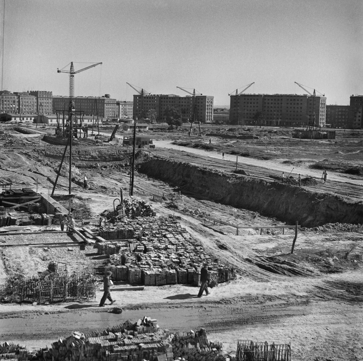 A view of the construction site from above, in the background a block of residential buildings.