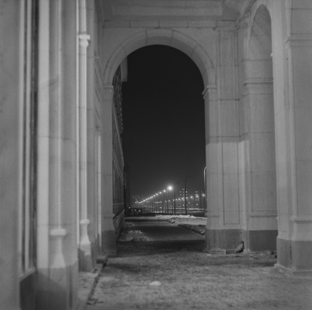 Night perspective of the illuminated street, shot from under the colonnade.