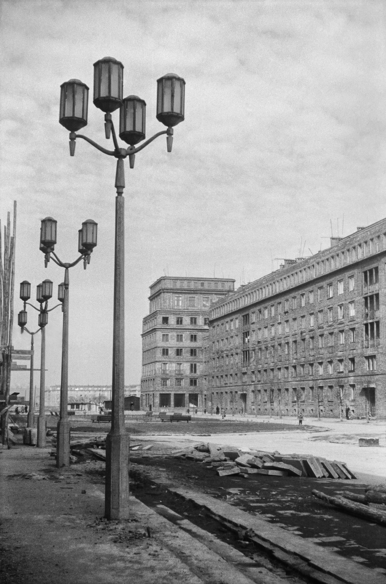 View of the representative city square under construction. Monumental lanterns in the foreground, residential buildings in the background.