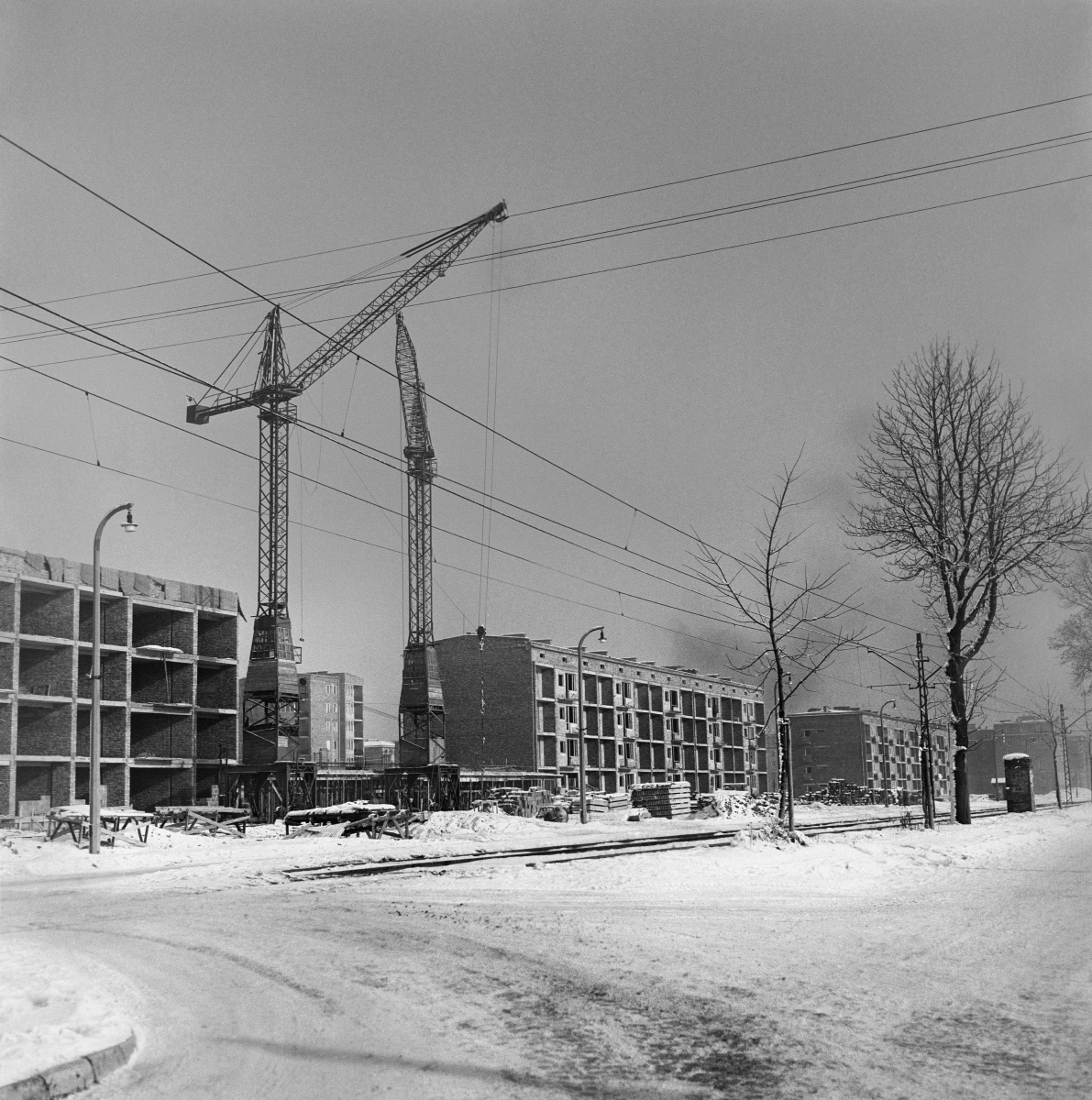 Construction of low blocks along the tram line. Old type construction cranes in the foreground. Winter shot.