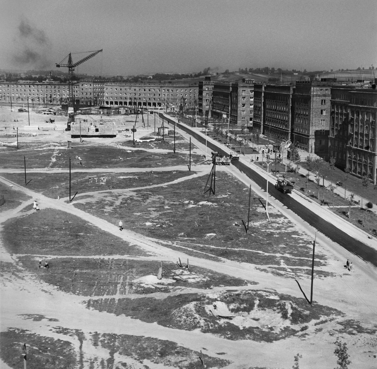 A view from above on the excavated, spacious square between the buildings under construction, which is crossed by paths trampled by pedestrians.