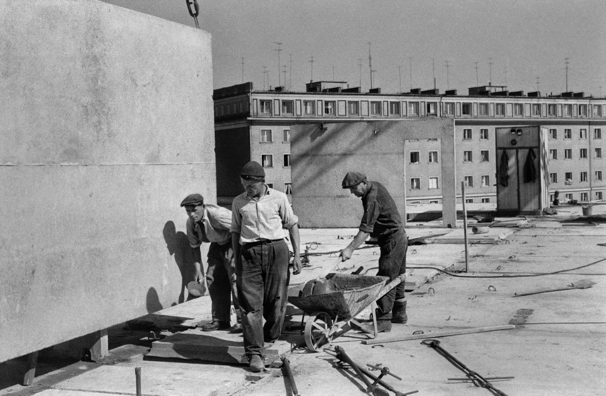 Workers prepare the ceiling of prefabricated panels for wall assembly.