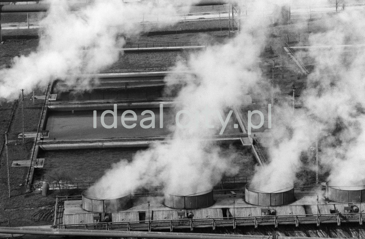 A view from above on the roof of the factory hall from which smoke is escaping from wide chimneys.