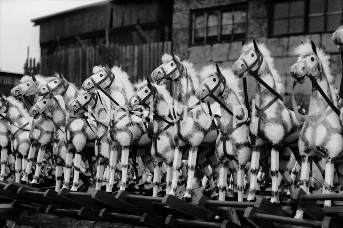 The shot shows a row of wooden rocking horses painted white.