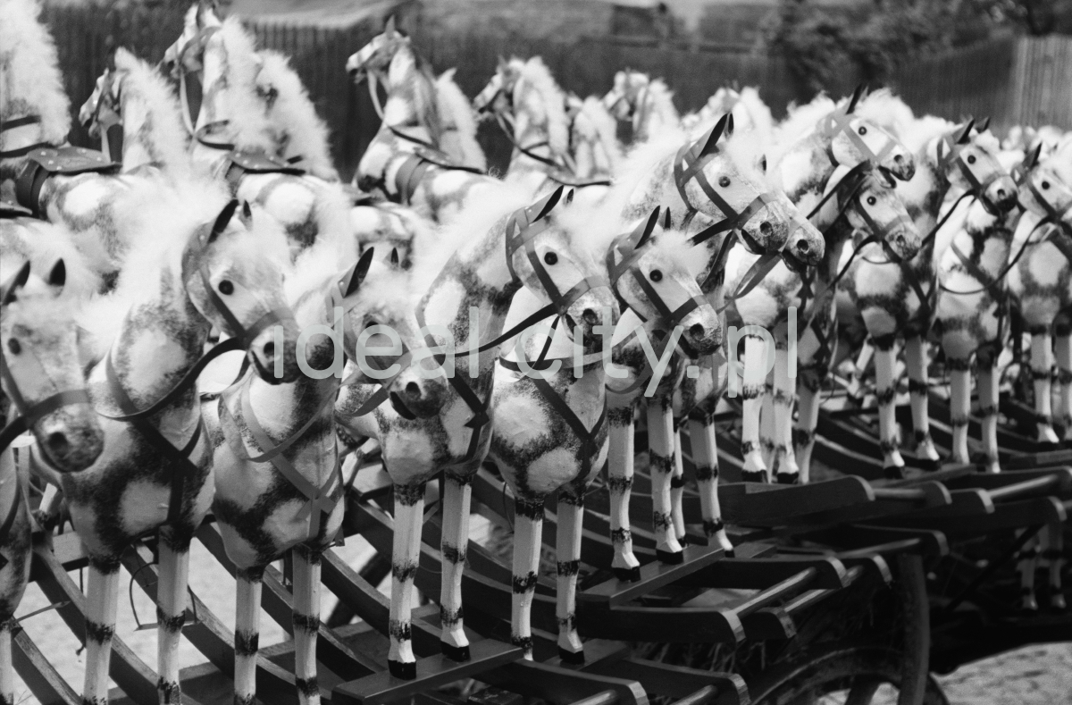 The shot shows a row of wooden rocking horses painted white.