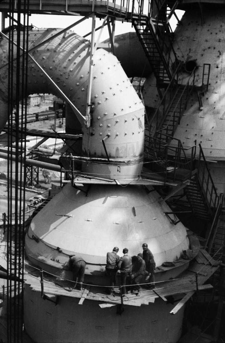 On the scaffolding set at a height, the men carry out assembly work on the huge tubular structure.