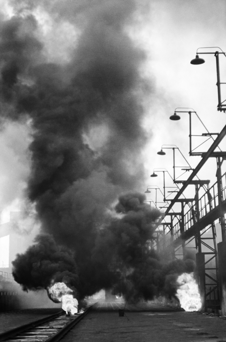A perspective, vertical shot of a series of smoky, openwork structures with lamps on top.