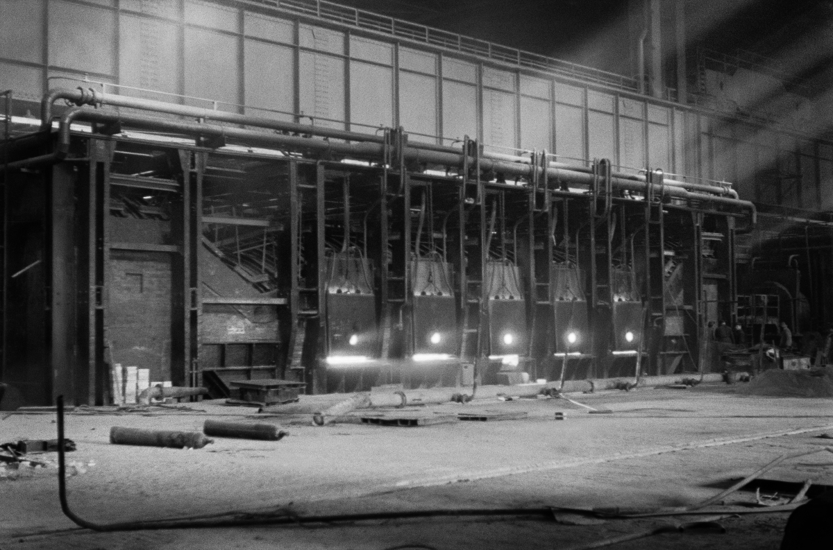A shot of a dark hall with a huge structure inside, on which rays of light fall from above.