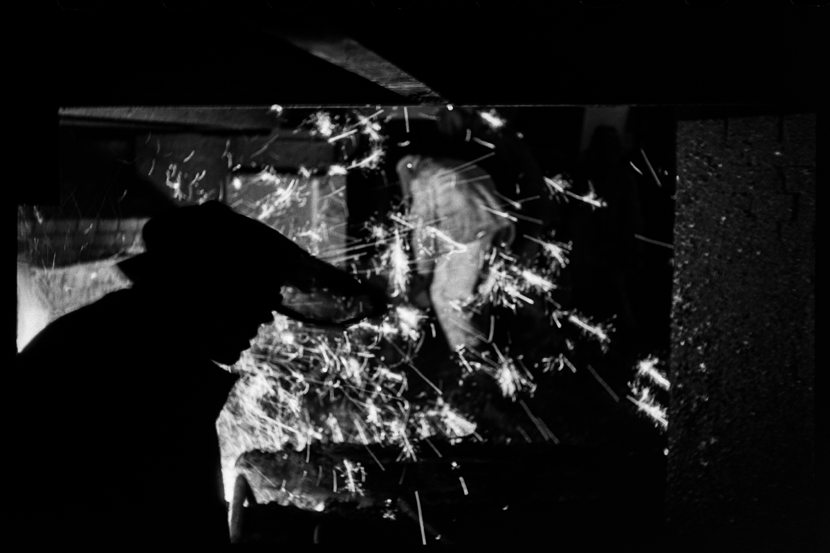 The outline of a steelworker in full clothes against the background of sparks.