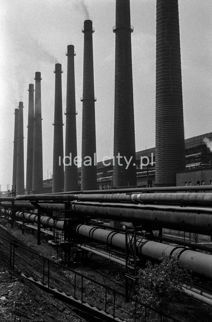 A shot of a series of successive high chimneys. On the right, a factory hall.