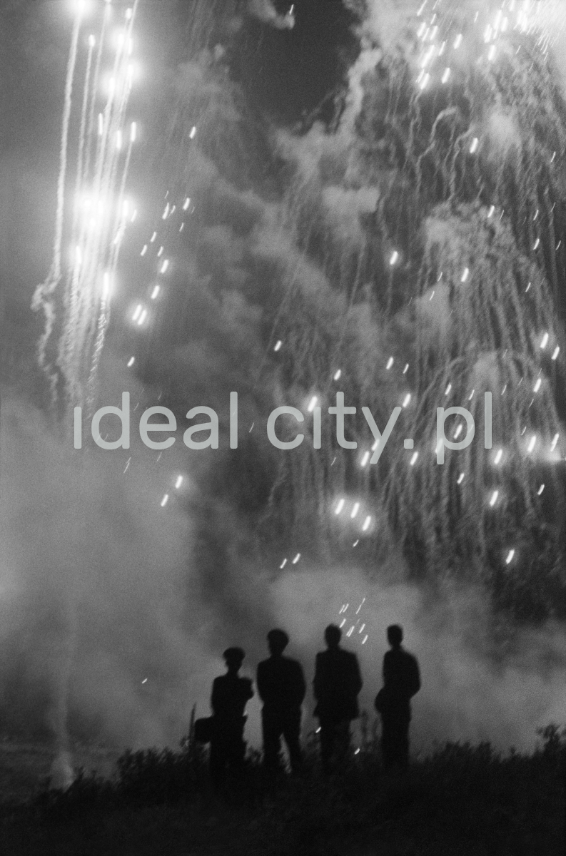Four figures in uniform watch the fireworks in the sky.