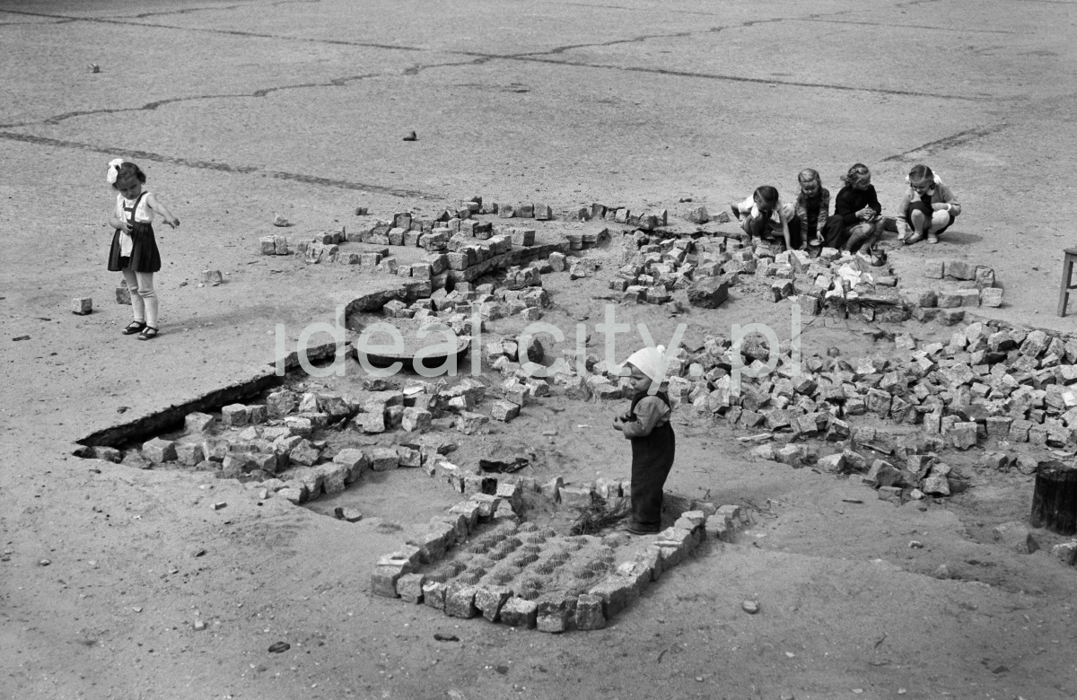 Children play with paving stones in an unfinished city square.