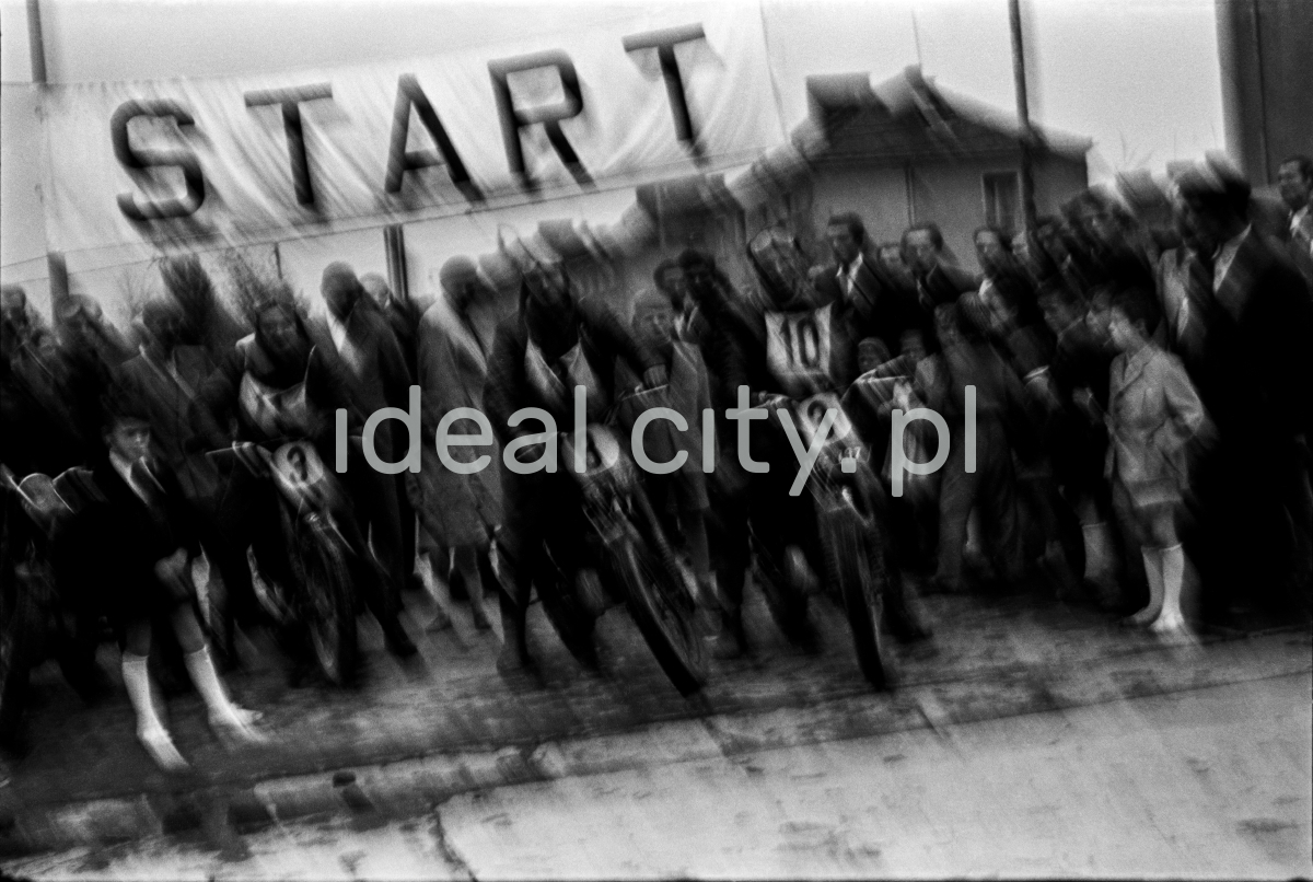 Moved photo of motorcyclists standing under the sign START.