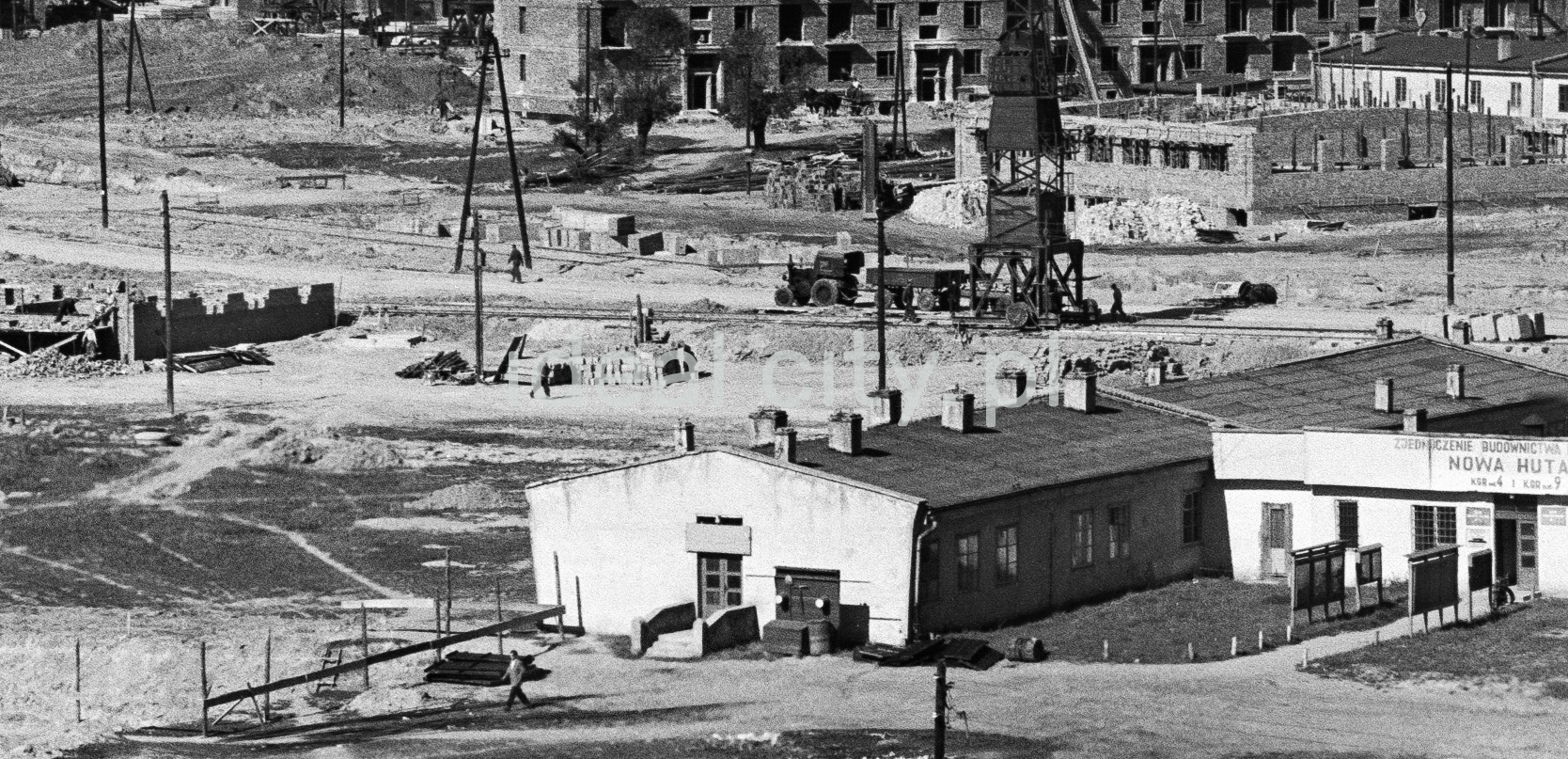A view from above of an unpaved square with office barracks.