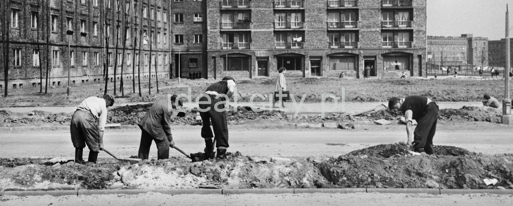 Workers carry out the finishing works along the street with shovels.