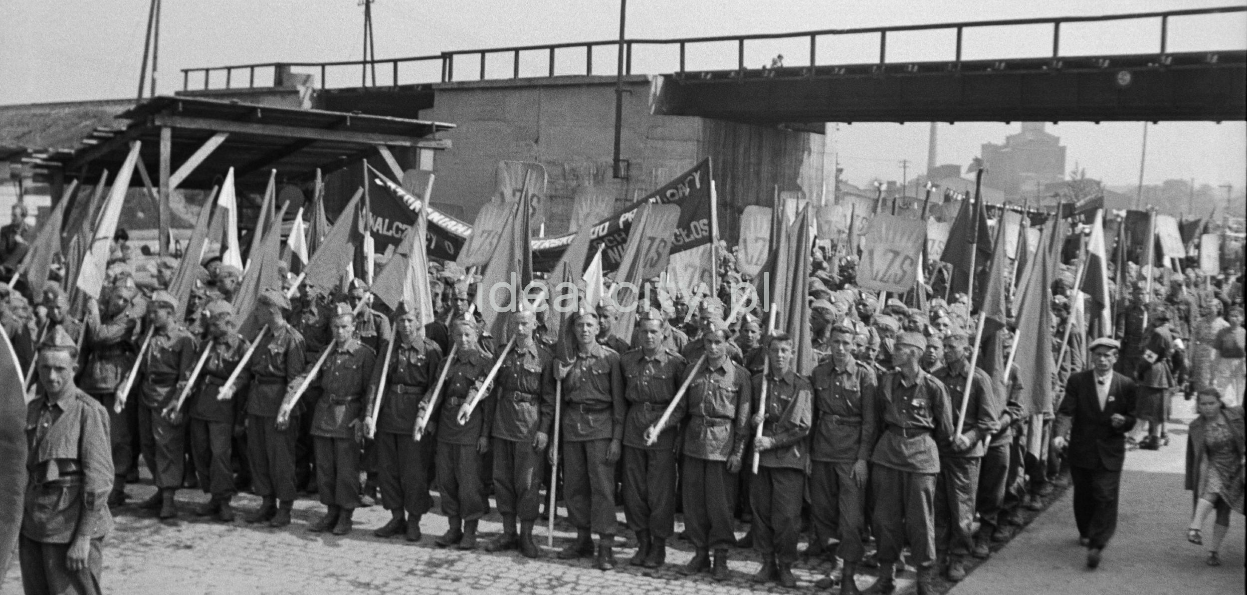 Young people dressed in uniforms march forward, holding flags in their hands.