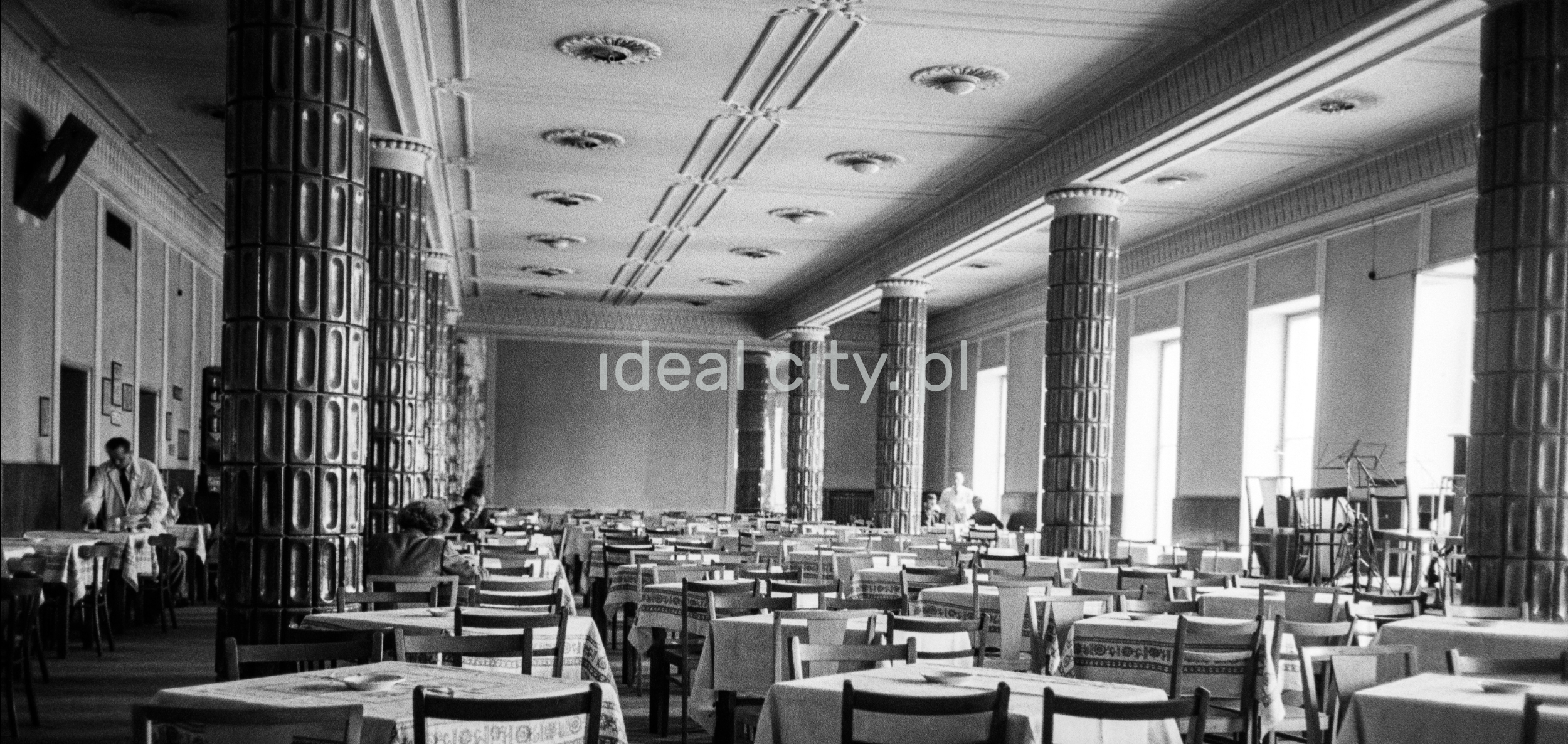 The perspective of the monumental interior of the restaurant, tables in the background and individual customers.