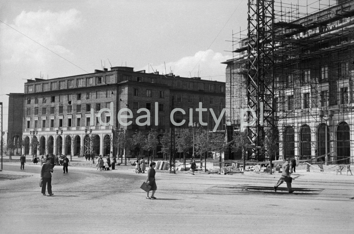 Pedestrian traffic in front of monumental residential buildings covered with scaffolding.