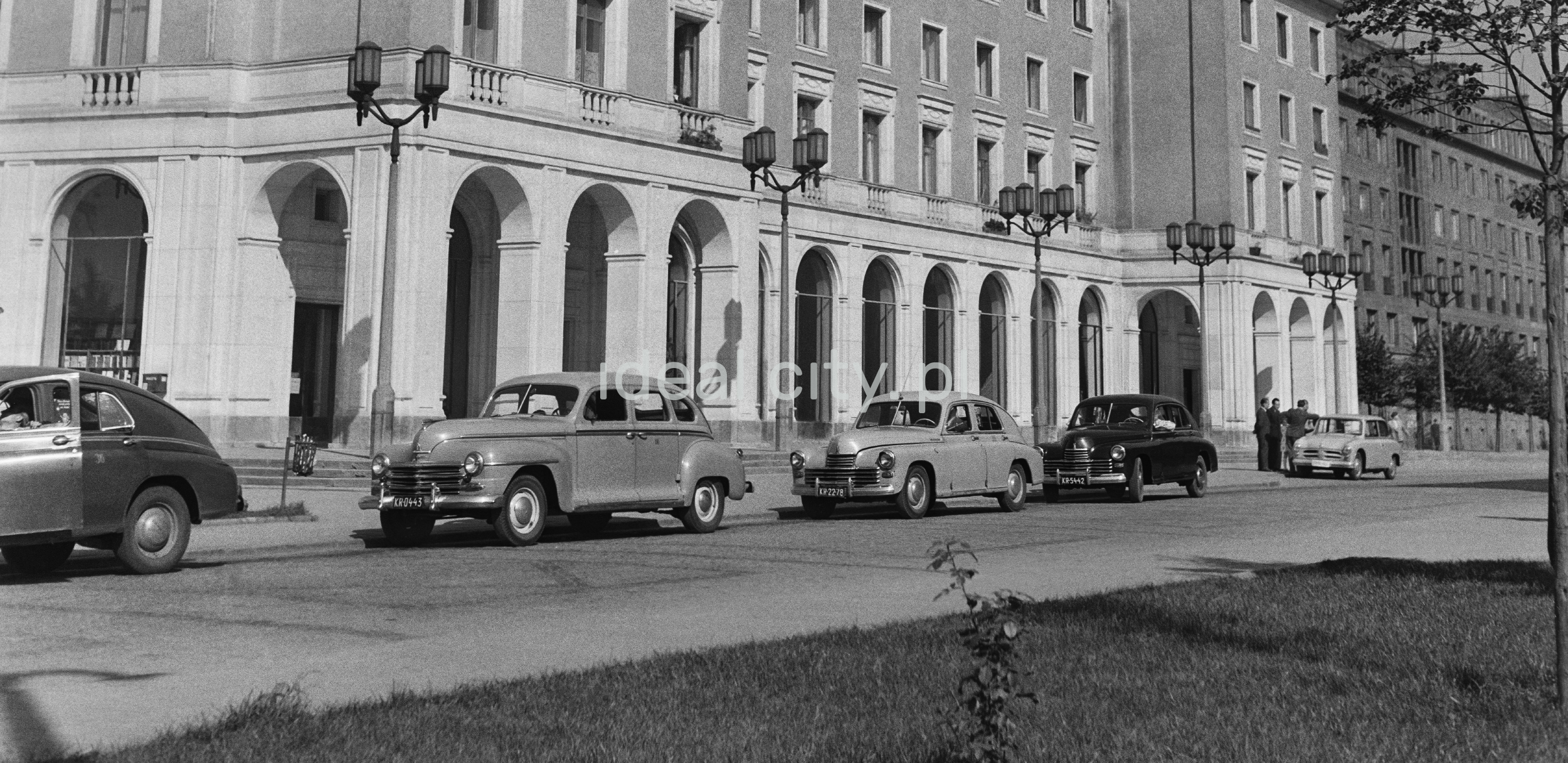A number of cars are waiting at the taxi stand, monumental architecture in the background.