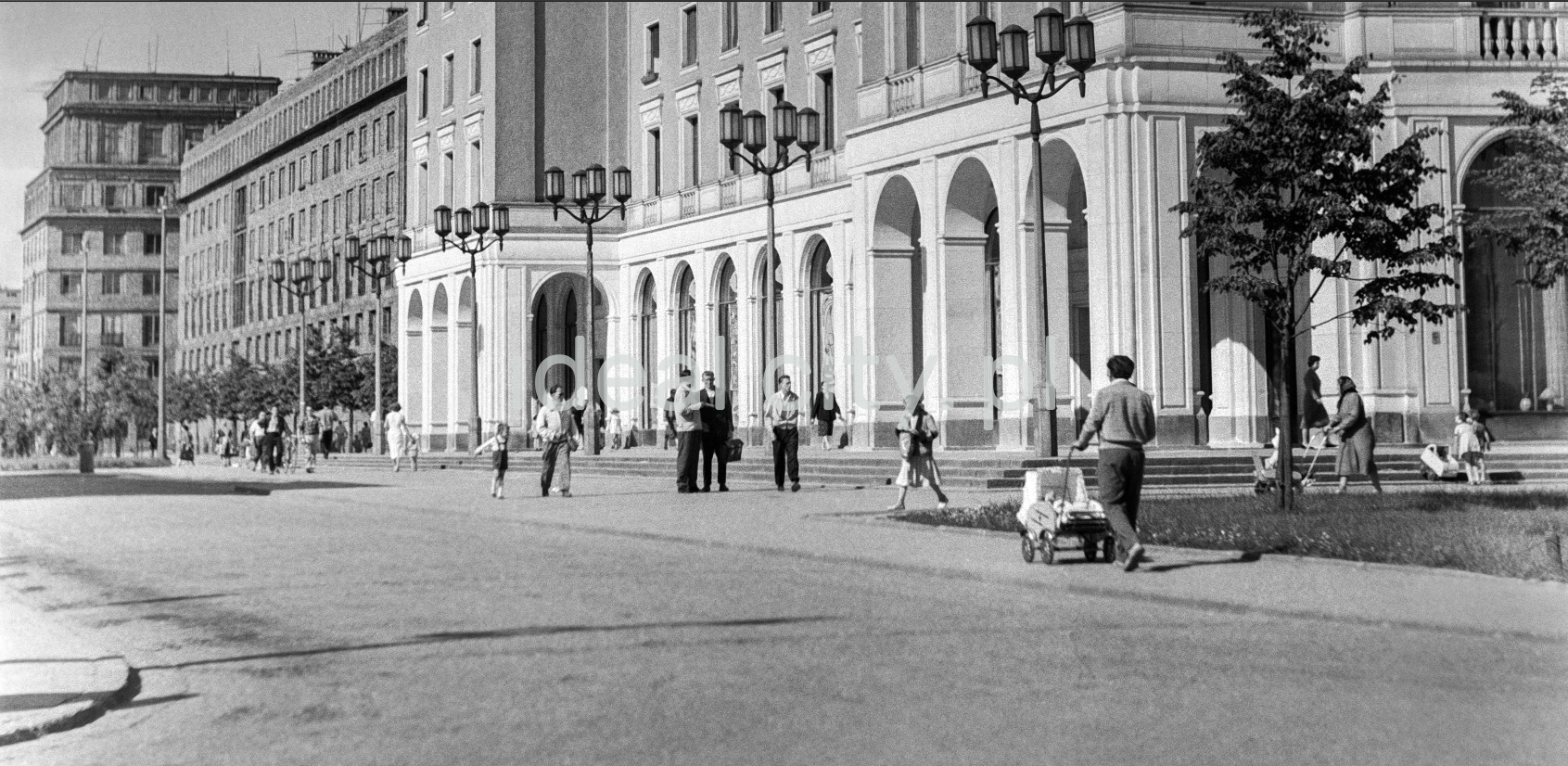 Pedestrian traffic in front of monumental buildings with arcades.
