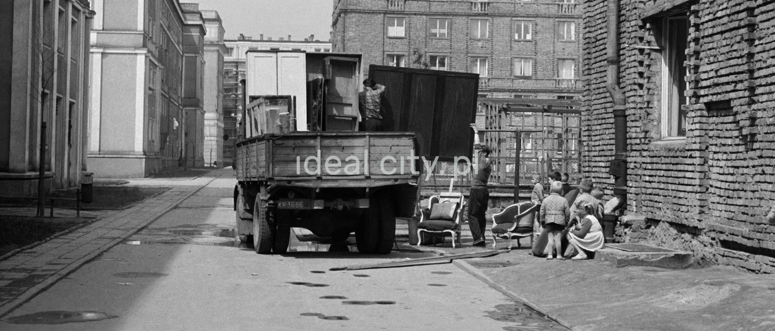 Several men are unpacking furniture from the transport car.