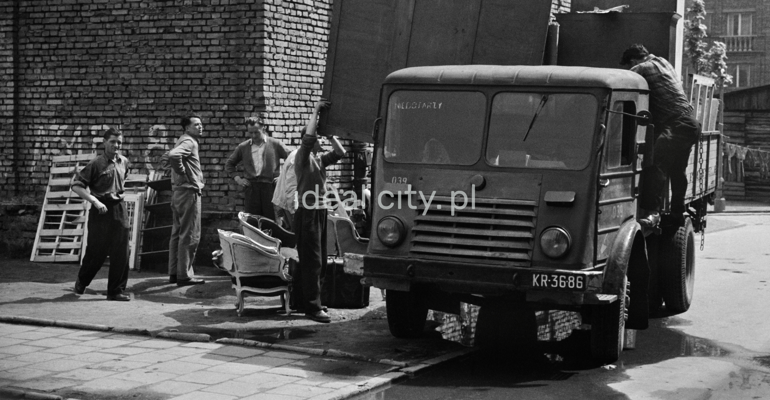 Several men are unpacking furniture from the transport car.