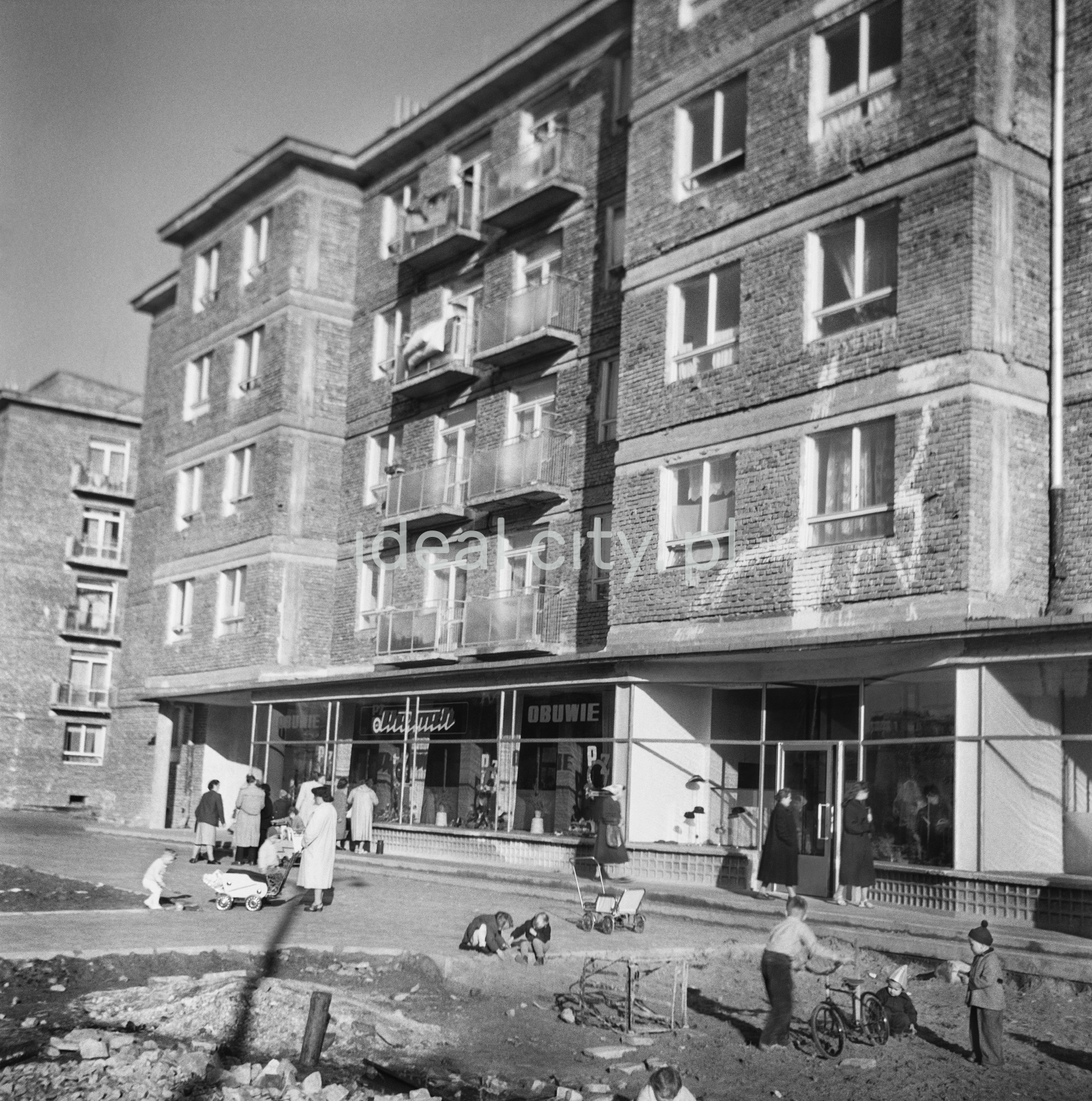 53/5000 Pedestrian traffic in front of an unplastered apartment block.