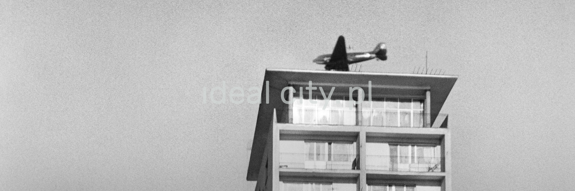 The bottom shot of the plane flying over the roof of the skyscraper.