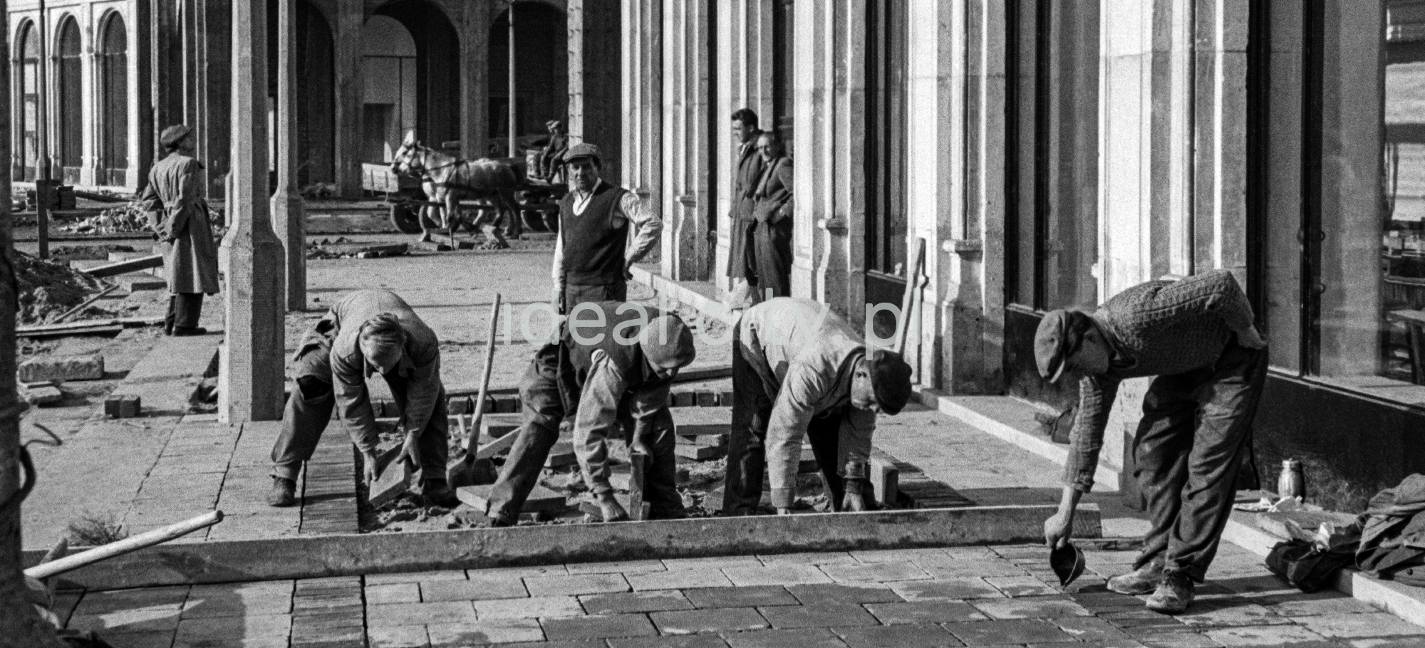 57/5000 Workers in working clothes are laying paving slabs.