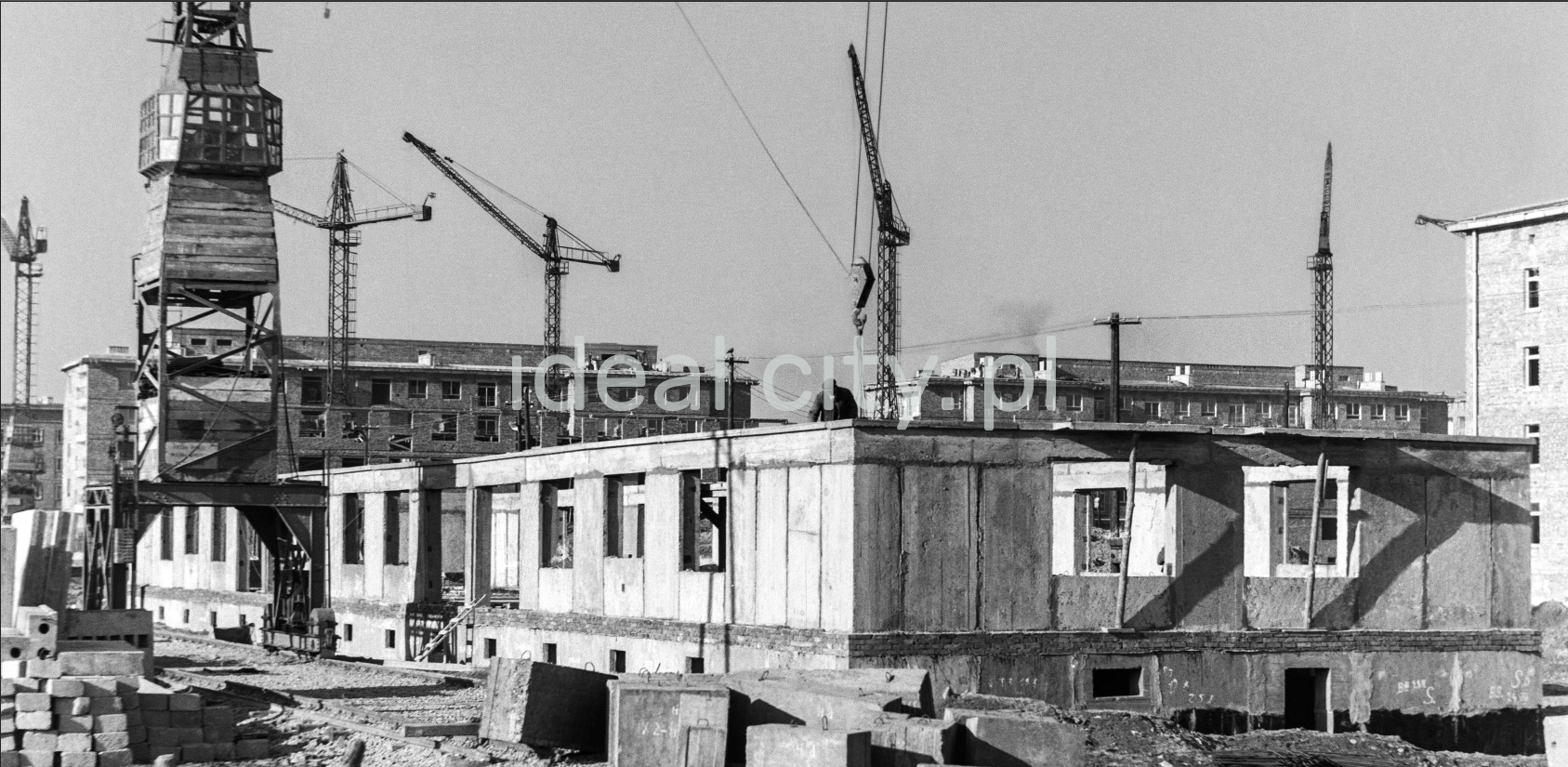 Visible the first storey of the building made of prefabricated panels, construction cranes around.