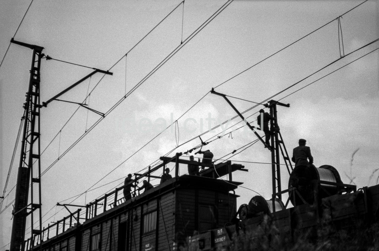 The workers, standing on the wagon's transport platform, assemble the cables.