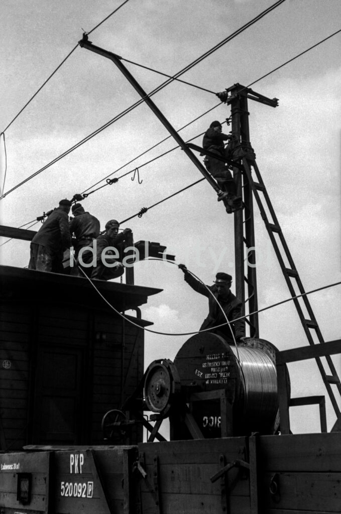 The workers, standing on the wagon's transport platform, assemble the cables.