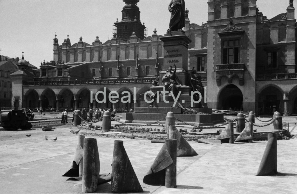 Freely arranged, unfolding rolls with tar paper, on the square of the city square with Renaissance buildings and a monument in the background.