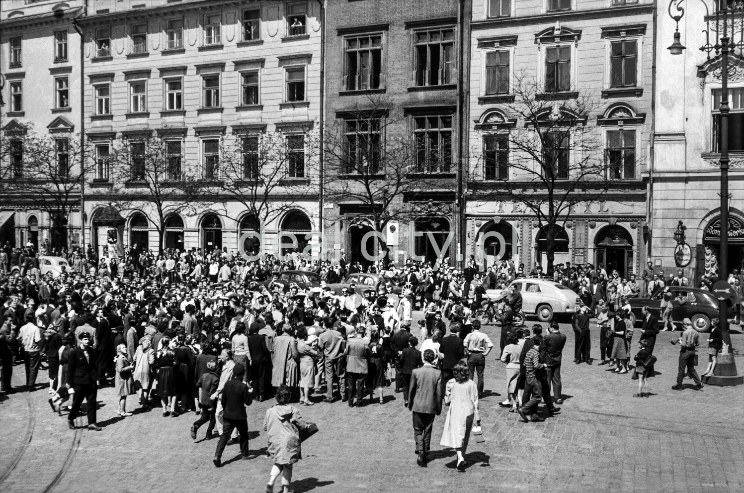 The crowd gathered in the town square, Renaissance tenement houses in the background.