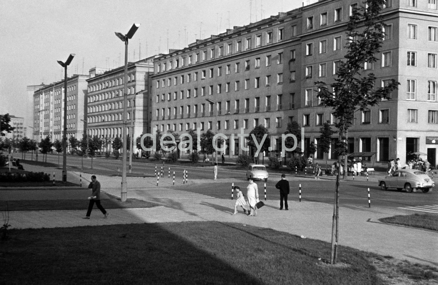 Little pedestrian traffic around the intersection, in the background a massive block of flats.