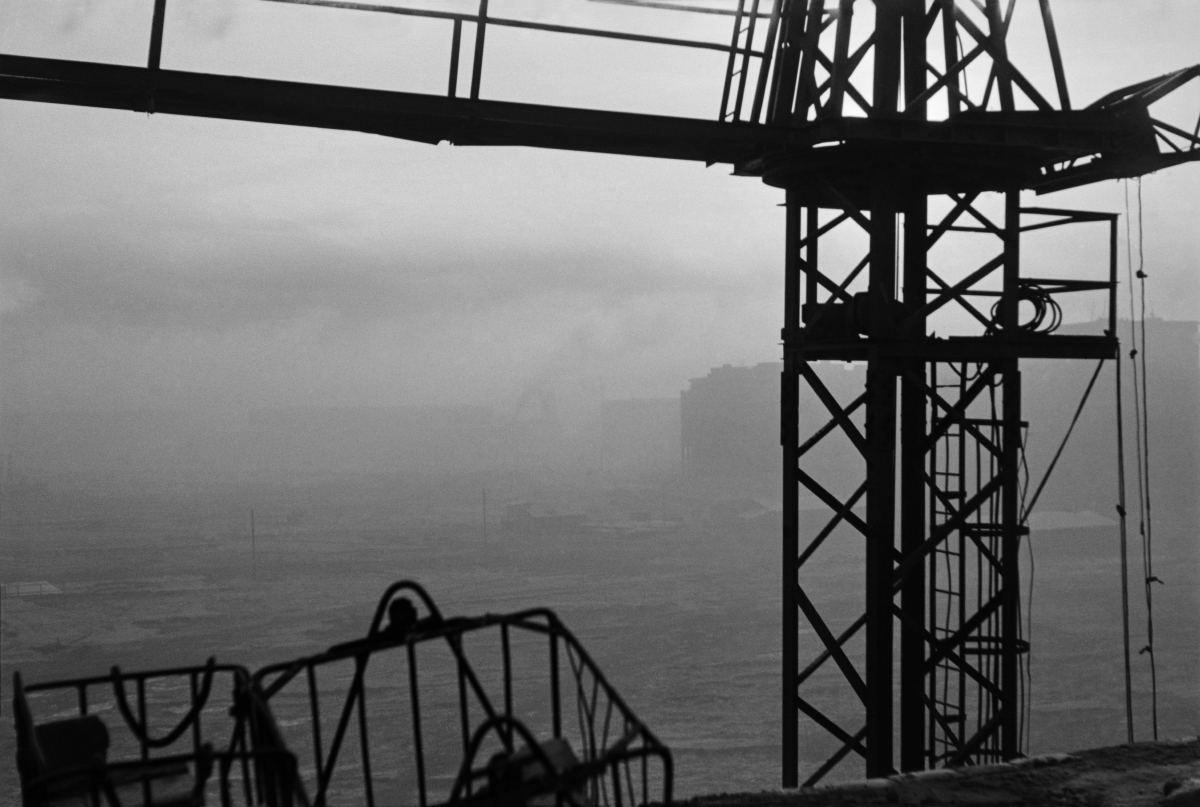 Top view over buildings plunged in fog through the construction crane structure.
