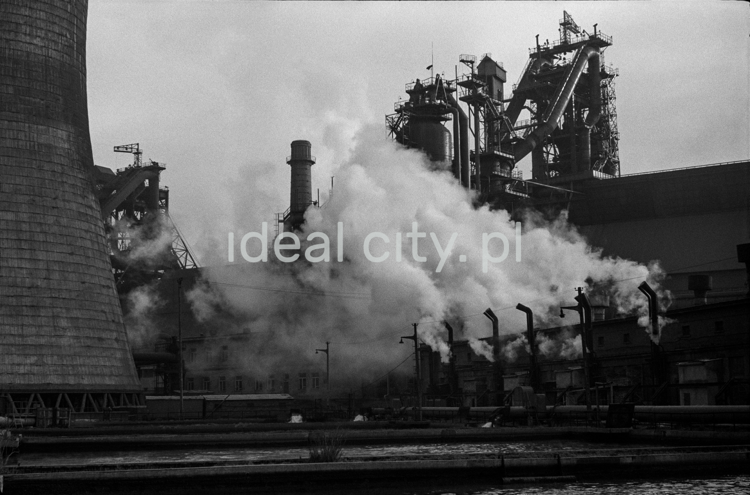 Ujęcie na ginące w dymach obiekty i kominy farbyczne w gęstej zabudowie.