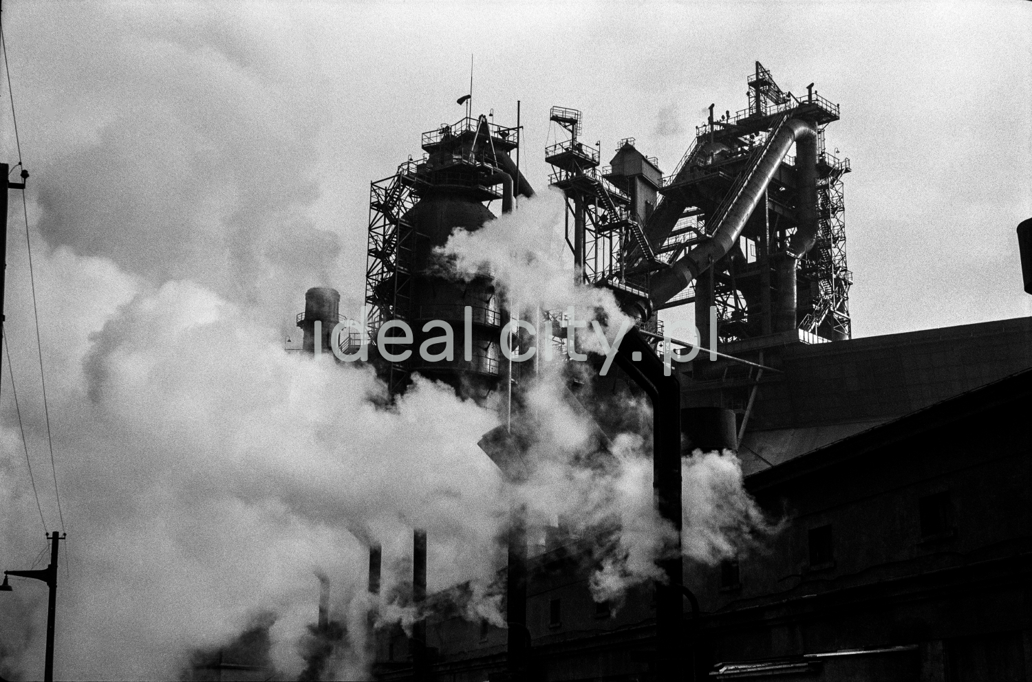 Ujęcie na ginące w dymach obiekty i kominy farbyczne w gęstej zabudowie.