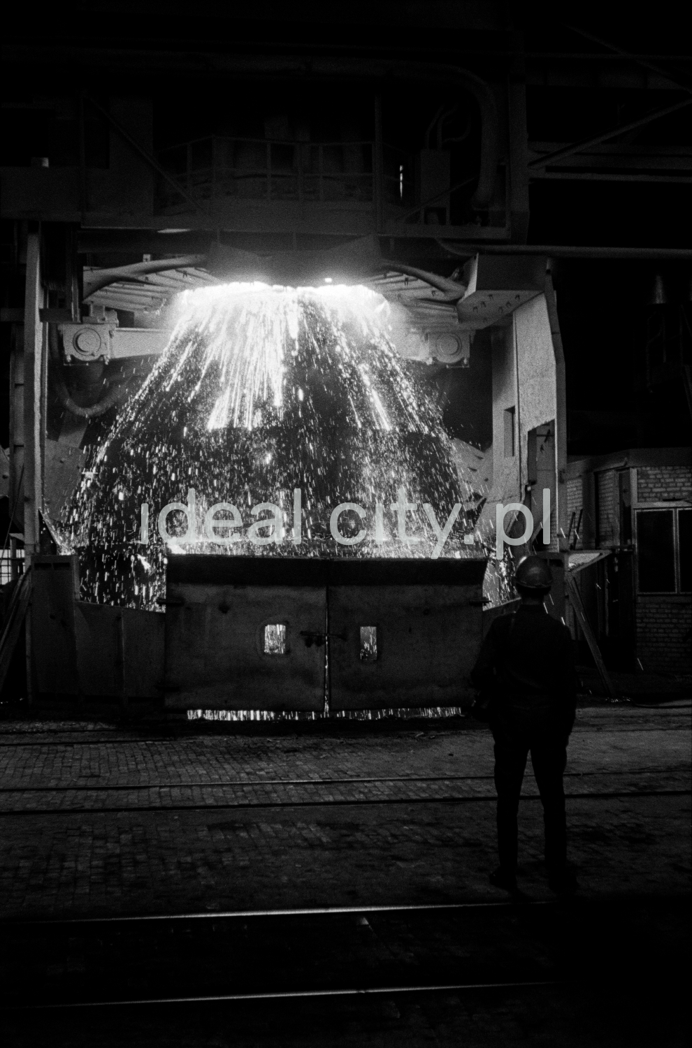 Hutnik obserwuje tryskającą z kadzi na boki surówkę.