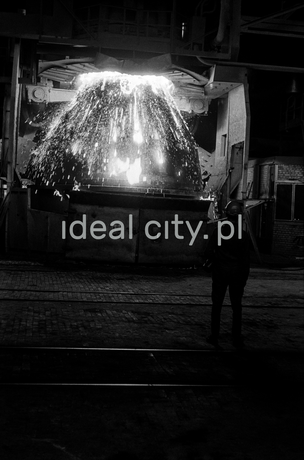 Hutnik obserwuje tryskającą z kadzi na boki surówkę.