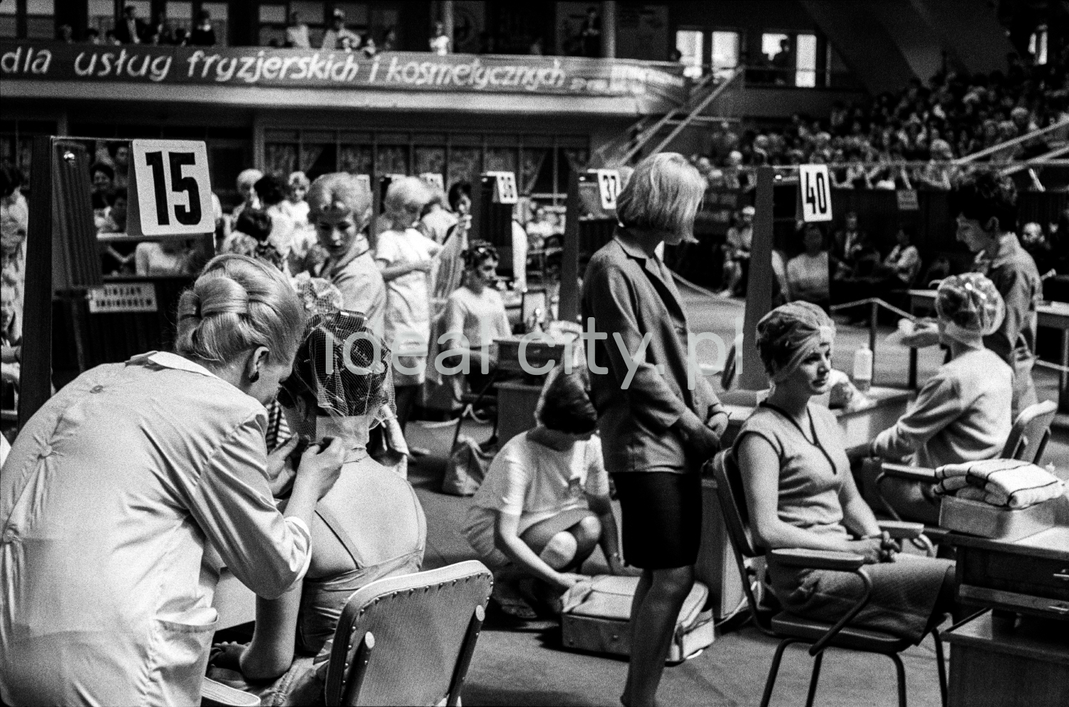 At the tables with numbers, the hairdressers prepare the women sitting at them.