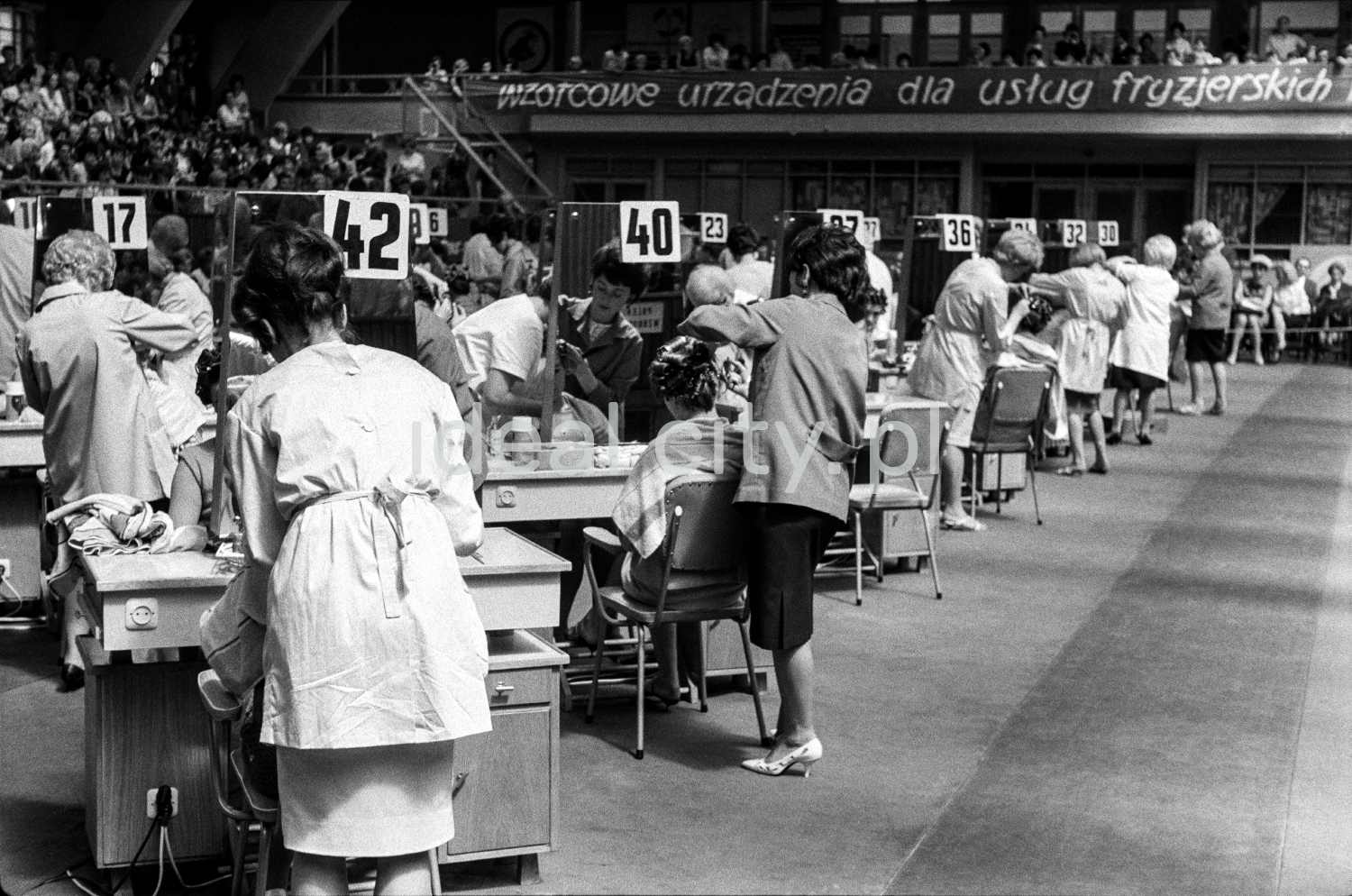 At the tables with numbers arranged in a row, the hairdressers prepare the women sitting at them.