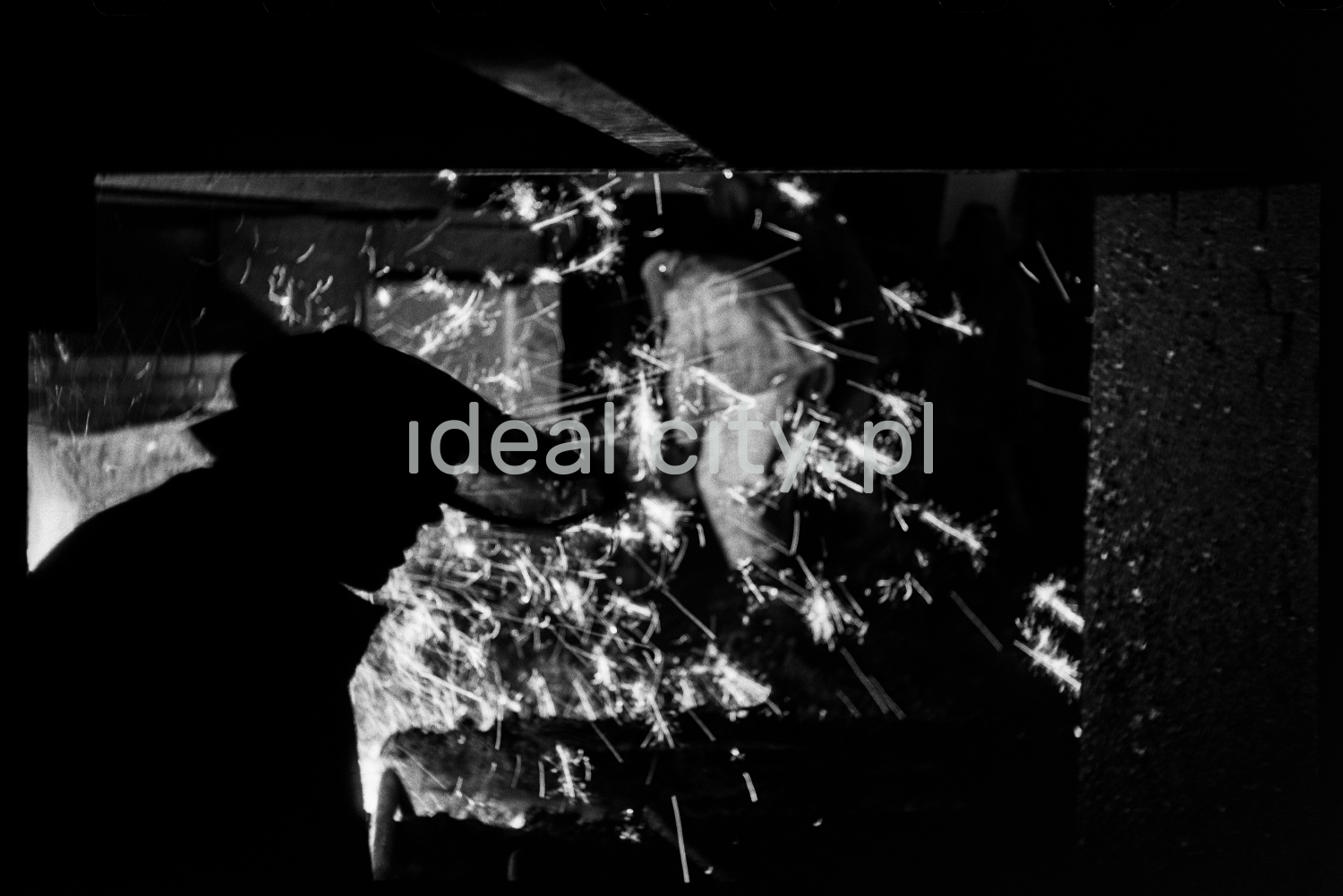 The outline of a steelworker with a raised visor against the background of a sparkling ladle.